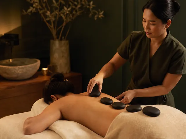 Therapist placing smooth basalt stones along a client's back during hot stone massage